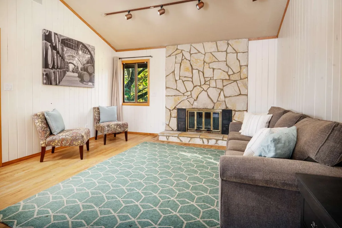 A cozy interior scene featuring a stone fireplace, plush sofa, and tasteful decor, creating a welcoming ambiance. The space is perfect for relaxing with family, friends, or pets after a day of outdoor activities.